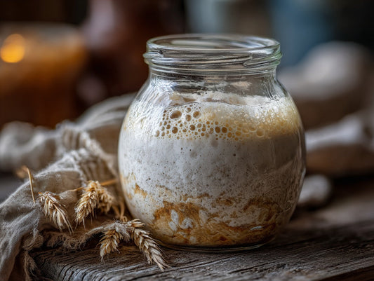 Wild yeast culture in a glass jar with wooden spoon nearby on a marble counter with flour dusting — sourdough starter feeding ratio guide guide from Mother's Country Store